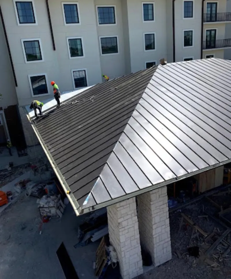 Crew installing standing seam metal roof panels on a commercial project in Powell